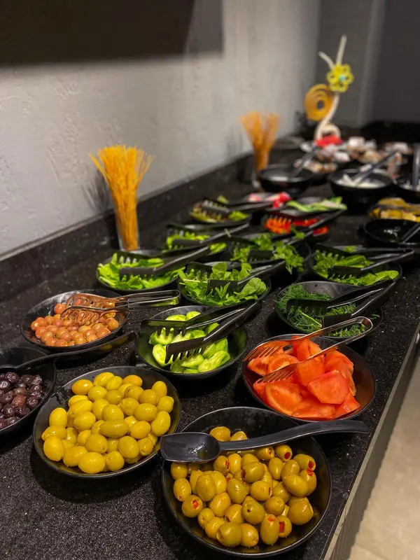 Un buffet propose une variété de salades, d'olives et de légumes.