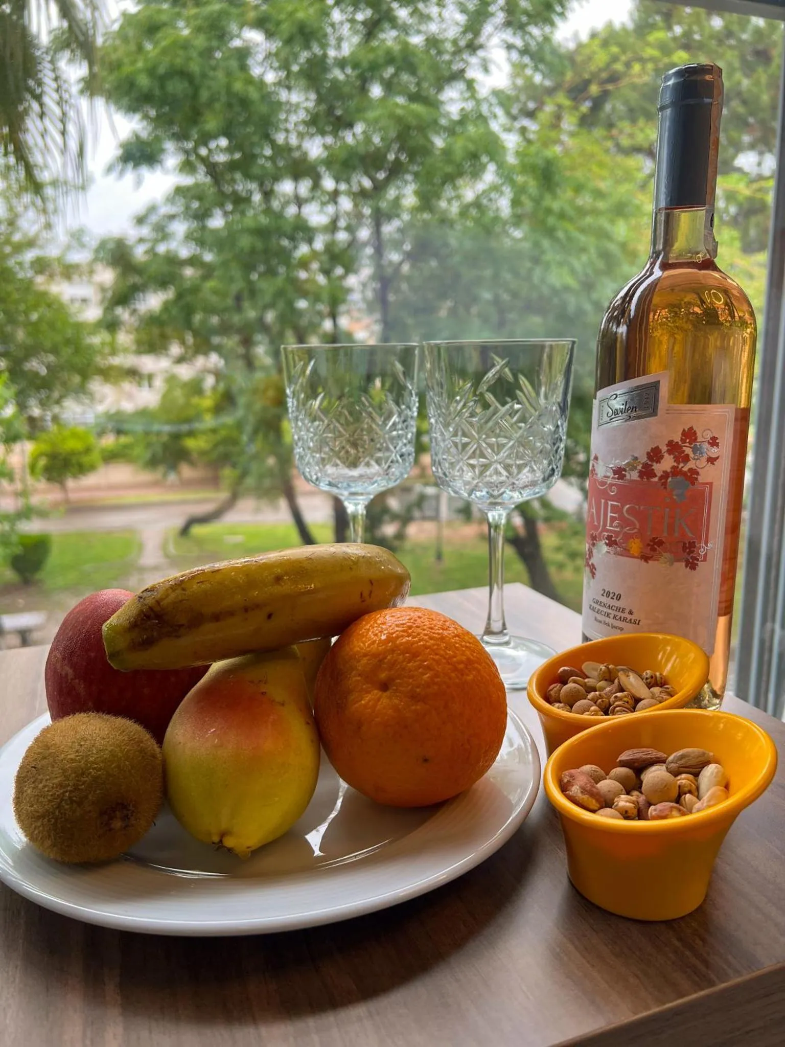 Nature morte avec des fruits, une bouteille de vin et des verres sur une table.
