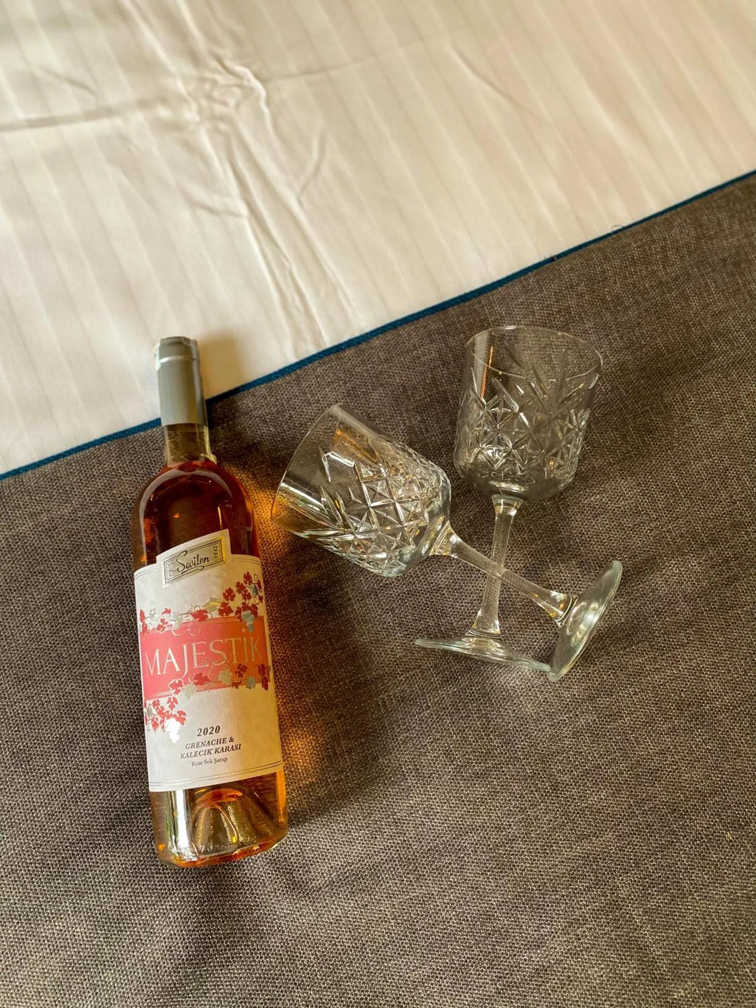 Une bouteille de vin et des verres sont posés sur un drap texturé.