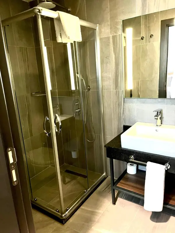 Une douche à l'italienne moderne avec des parois vitrées et un lavabo.