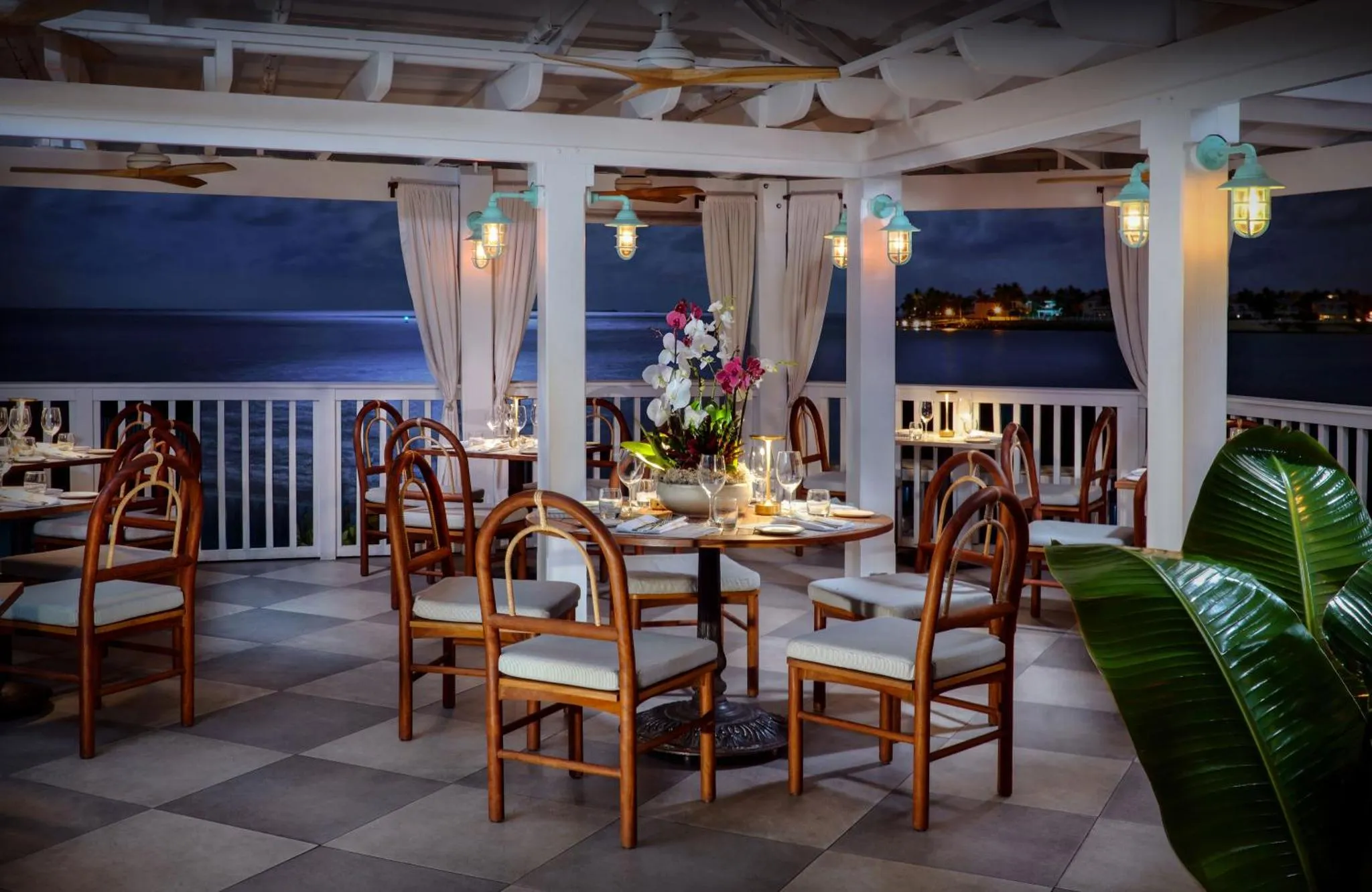 Une terrasse ombragée avec des tables dressées pour le dîner en bord de mer.