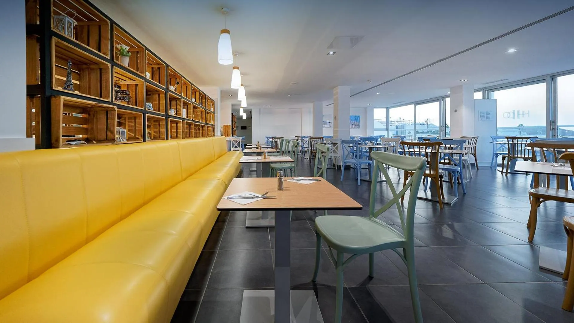 Une salle lumineuse avec des tables et des banquettes colorées.