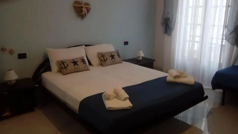 Une chambre avec un grand lit recouvert d'une courtepointe bleue et blanche.