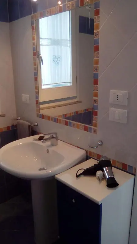 Une salle de bain claire avec un lavabo et un sèche-cheveux.