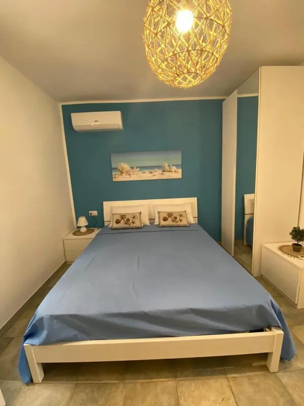 Une chambre lumineuse avec un grand lit recouvert d'une couverture bleue.