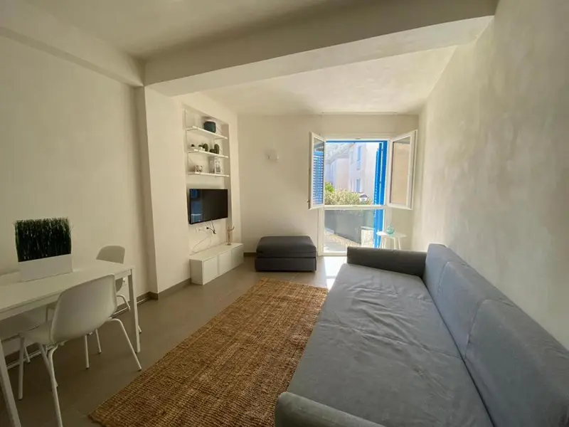 Espace de vie lumineux avec canapé, bureau et télévision.
