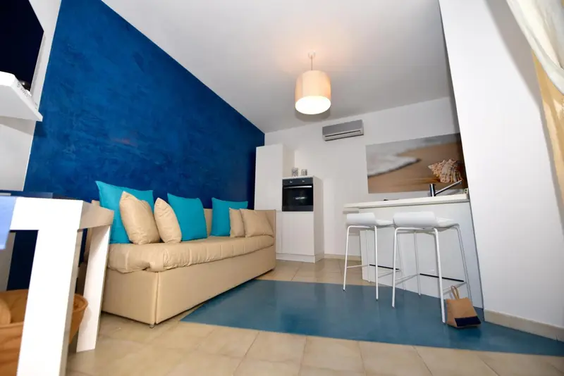 Espace de vie intérieur avec canapé beige et cuisine équipée.