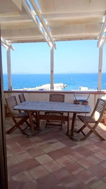 Une table et des chaises en bois sur une terrasse carrelée avec vue sur la mer.
