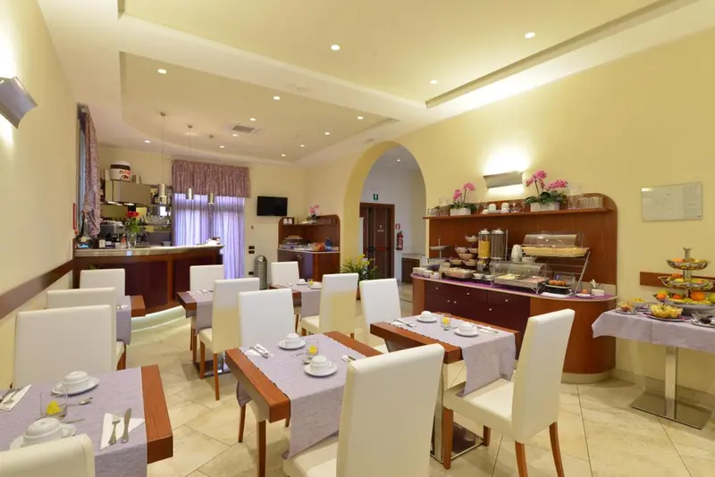 Une salle lumineuse avec des tables dressées pour le petit-déjeuner.
