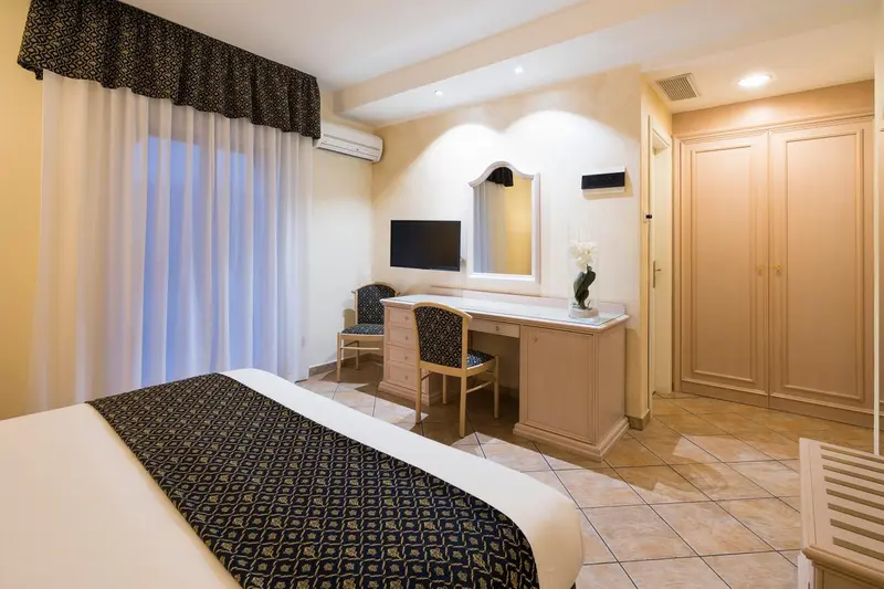 Une chambre lumineuse avec un lit, un bureau et une armoire.