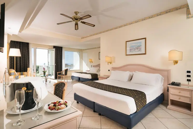 Chambre lumineuse avec un grand lit et une vue sur la mer.