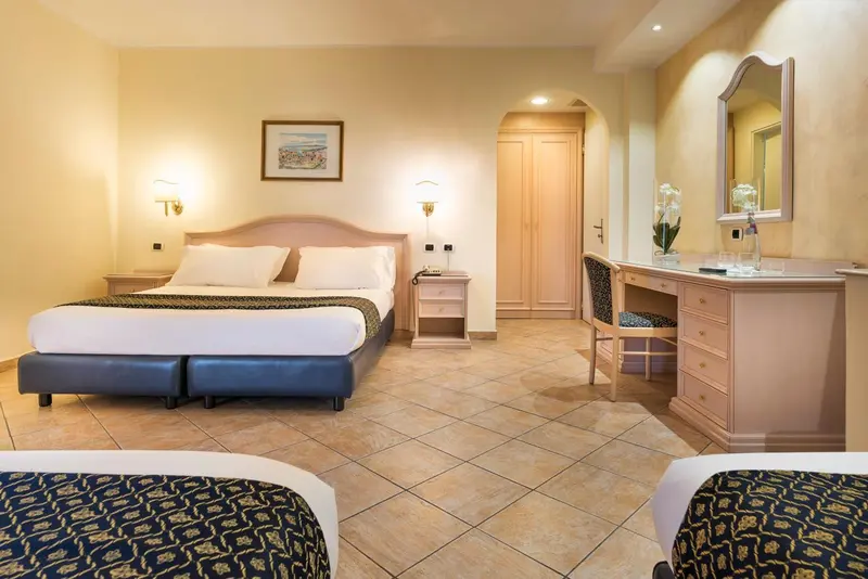 Chambre lumineuse avec un grand lit et un coin coiffeuse.