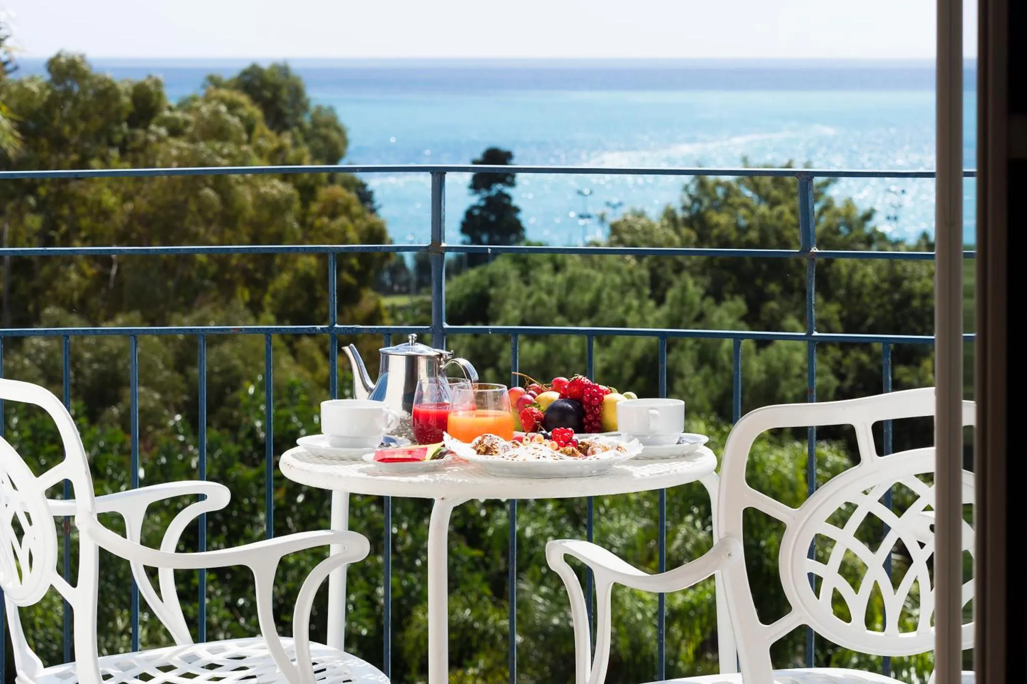 Une table avec un petit-déjeuner est mise en scène sur une terrasse avec vue sur la mer.