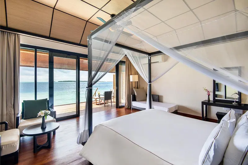 Une chambre lumineuse avec un lit à baldaquin donnant sur l'océan.