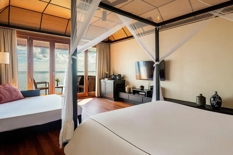 Une chambre lumineuse avec un lit et un canapé face à une baie vitrée.