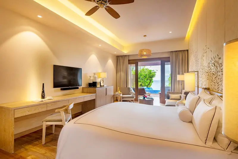 Une chambre lumineuse avec un grand lit et un espace salon.
