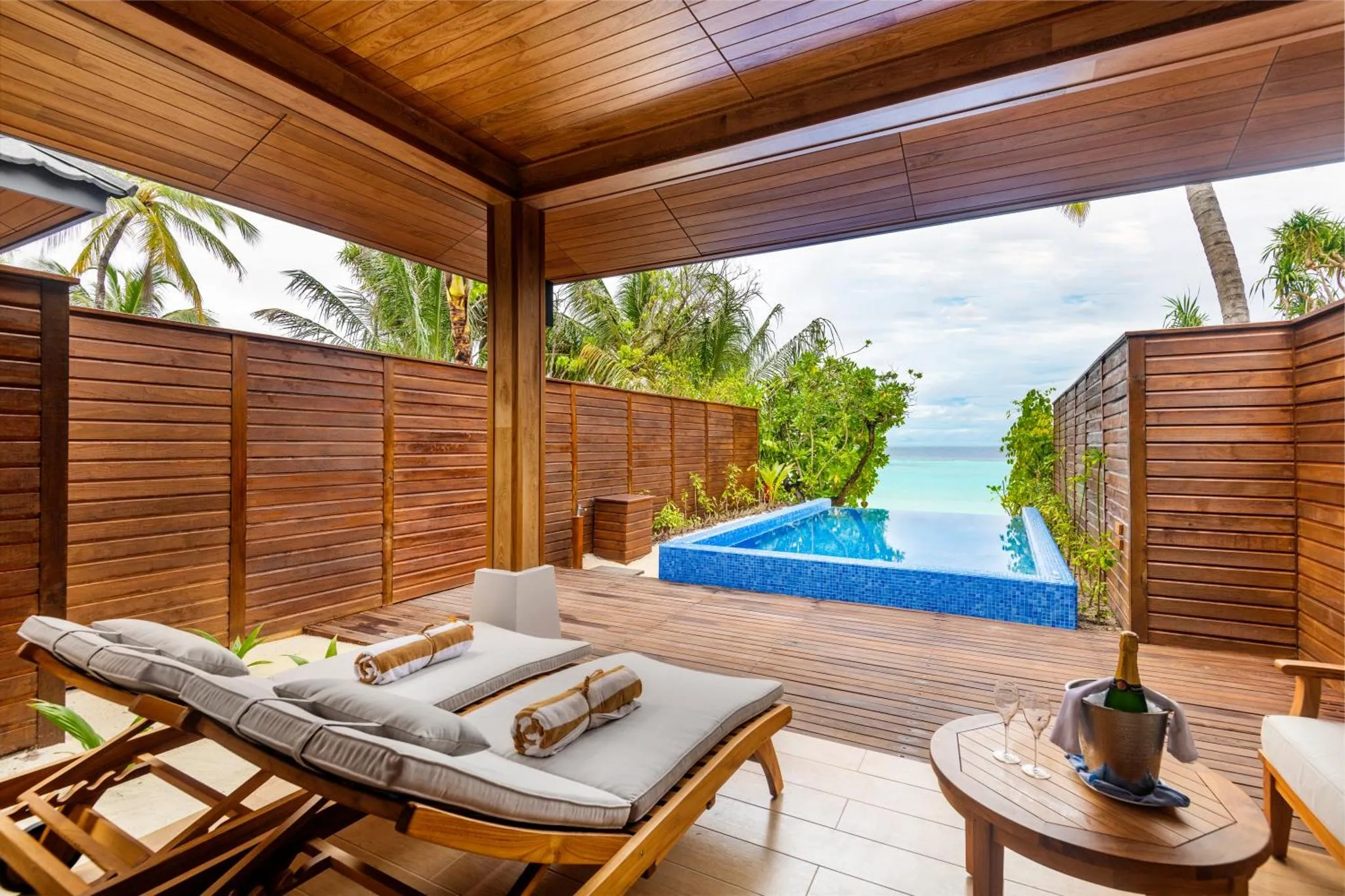 Terrasse en bois avec transats et petite piscine donnant sur la mer.