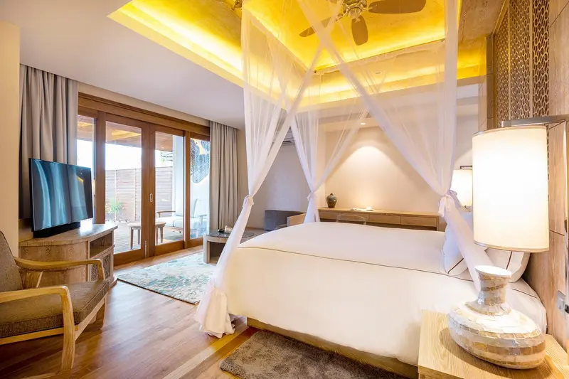Une chambre lumineuse avec un grand lit à baldaquin et un accès à une terrasse.