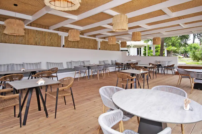 Espace de restauration extérieur avec tables et chaises en osier.