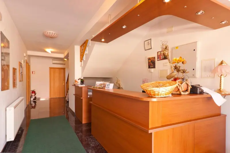 Un comptoir d'accueil en bois clair dans un hall d'hôtel.