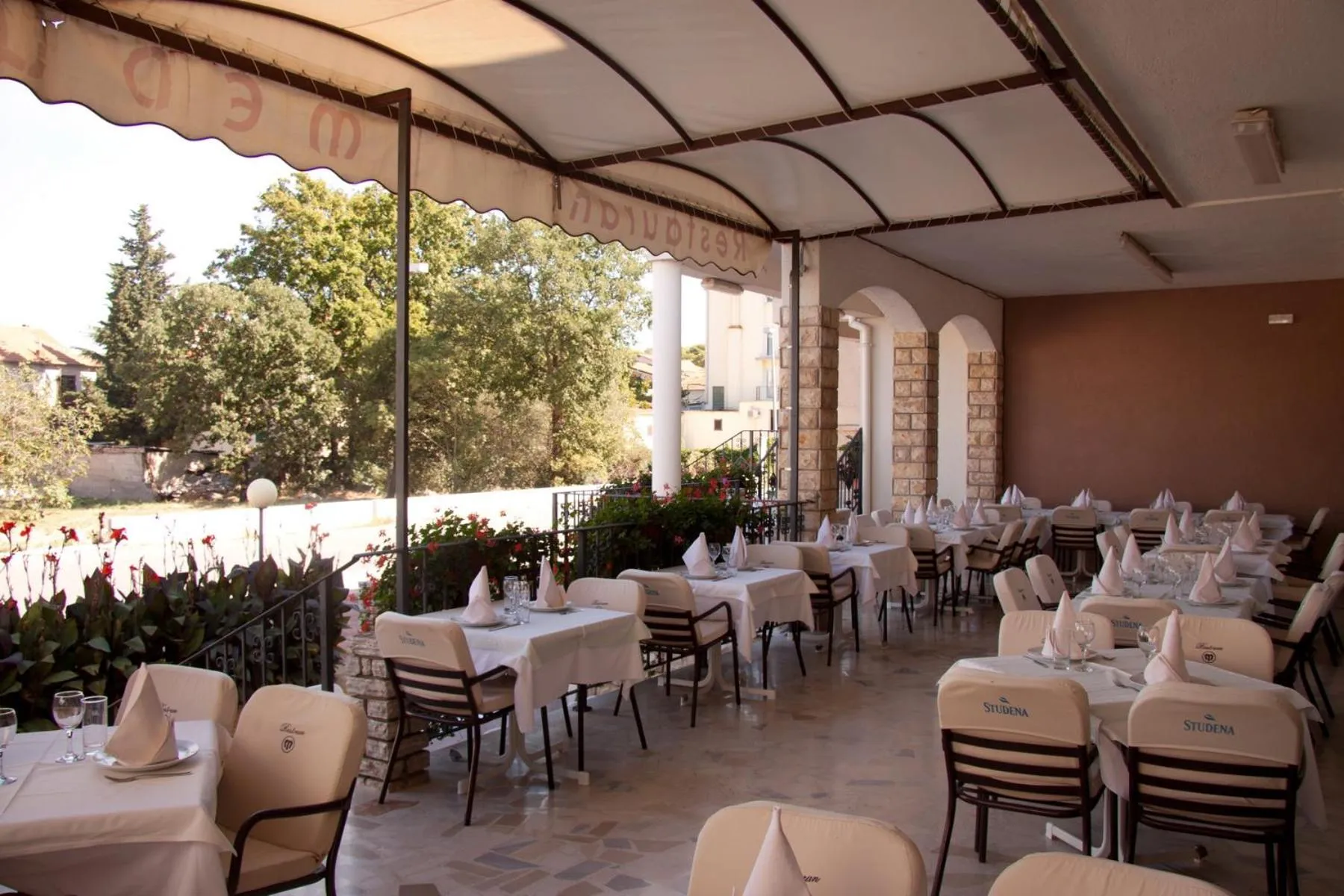 Une terrasse ombragée avec des tables dressées pour un repas.
