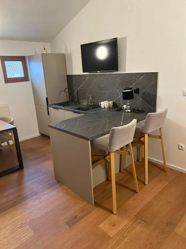 Une petite cuisine moderne avec un bar et deux tabourets.