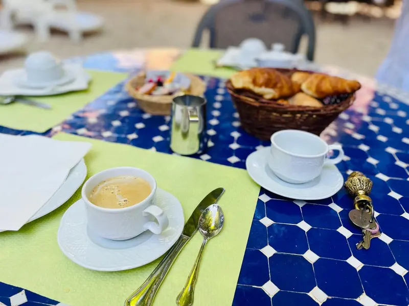 Une table est dressée avec des viennoiseries, des couverts et des boissons.