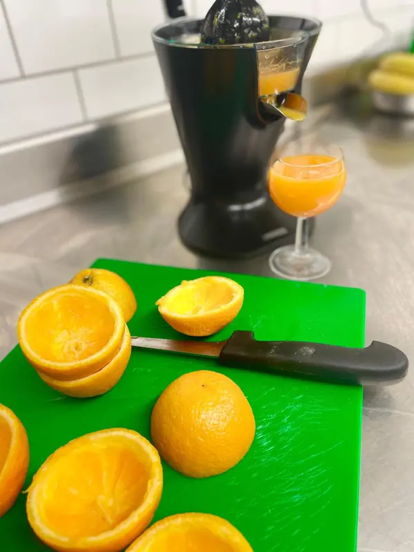 Une planche à découper avec des oranges coupées et un presse-agrumes.