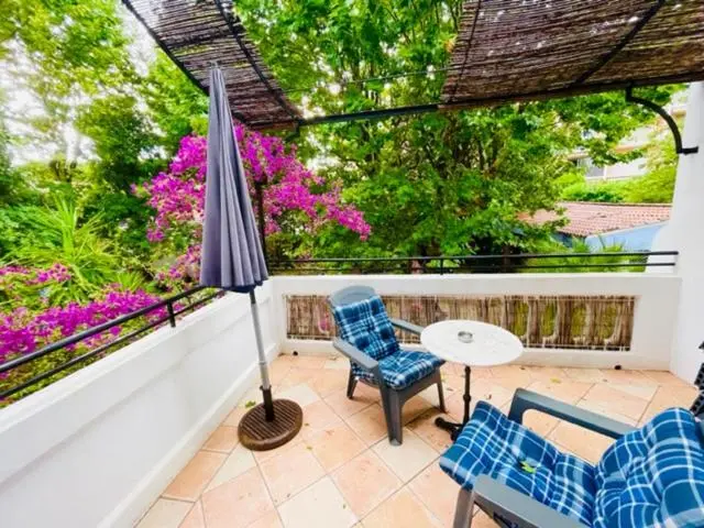 Terrasse carrelée avec mobilier de jardin et végétation luxuriante.
