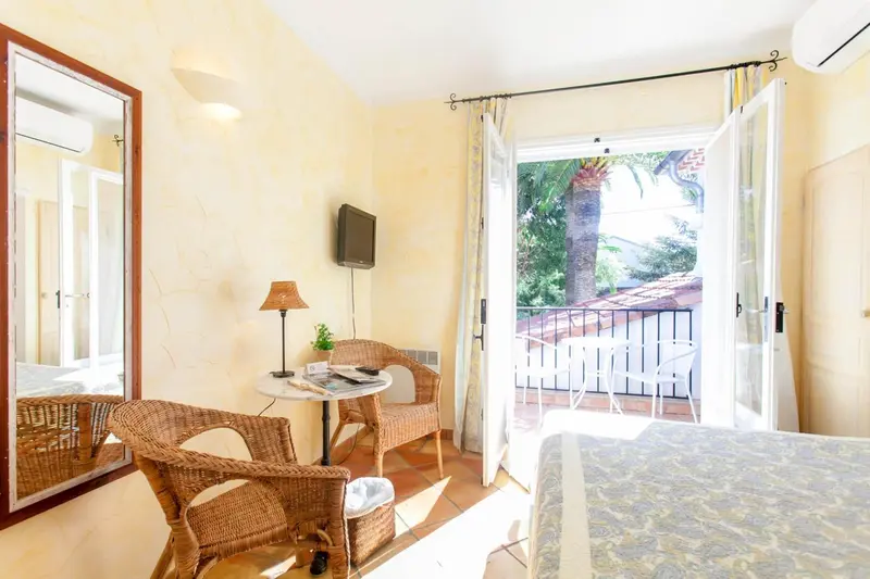 Une chambre lumineuse avec un coin salon et un balcon fleuri.