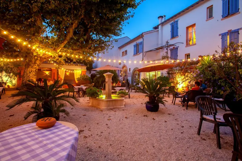 Une cour intérieure illuminée avec des tables et une fontaine.