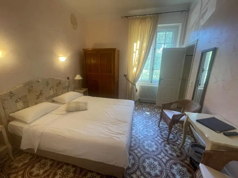Une chambre lumineuse avec un grand lit et un bureau.