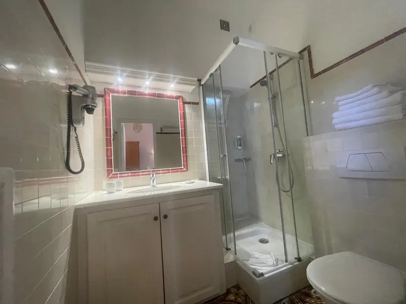 Une salle de bain lumineuse avec douche vitrée et lavabo.