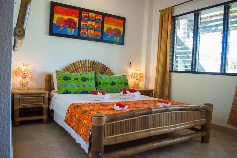 Une chambre lumineuse avec un lit recouvert de motifs colorés et décoré de fleurs.