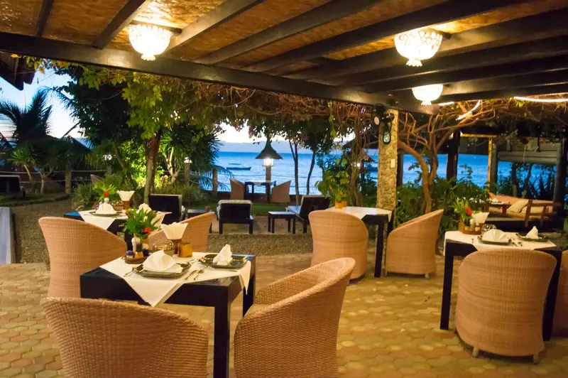 Une terrasse de restaurant avec des tables dressées face à la mer.