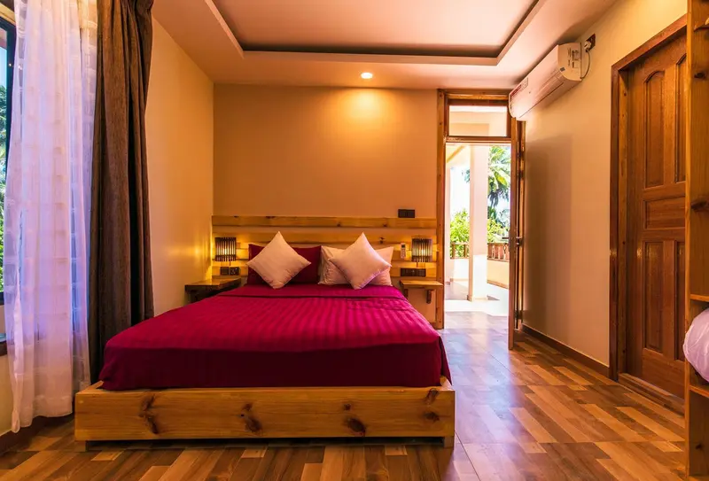 Une chambre aux murs beiges et au lit recouvert d'une courtepointe rouge.