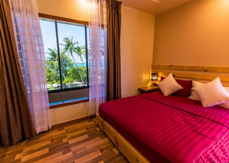Une chambre lumineuse avec un grand lit et une vue sur la végétation tropicale.