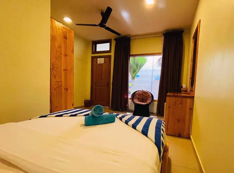 Une chambre lumineuse avec un lit recouvert d'un couvre-lit rayé et un coin salon.