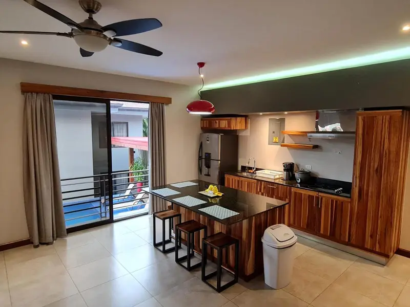 Une cuisine moderne s'ouvre sur un espace de vie lumineux avec vue sur une piscine.