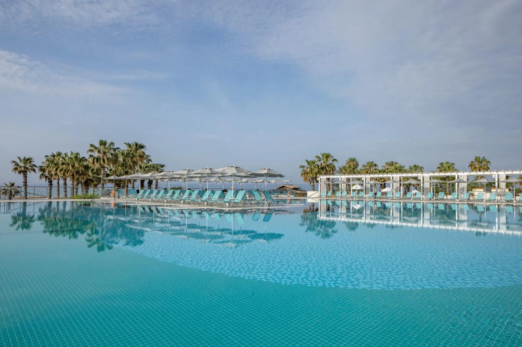 Transats alignés au bord d'une piscine à débordement avec vue sur la mer.