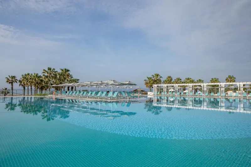 Transats alignés au bord d'une piscine à débordement avec vue sur la mer.