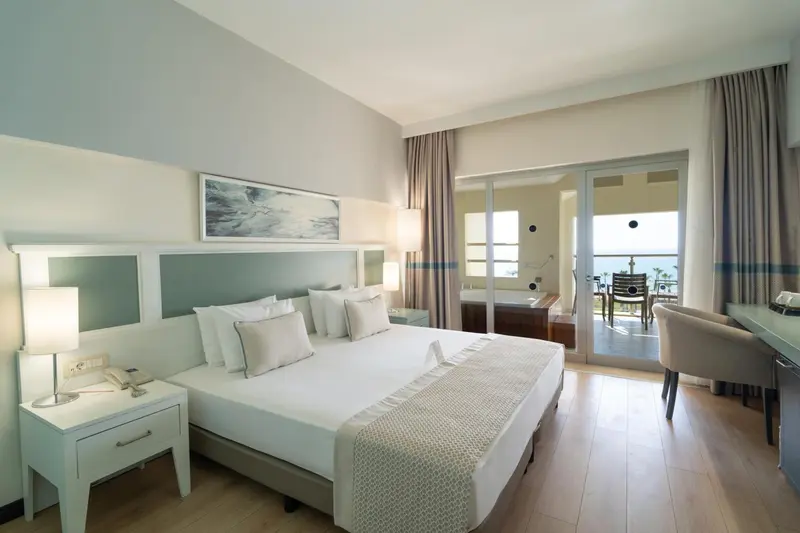 Une chambre lumineuse avec un grand lit et un accès à une terrasse.