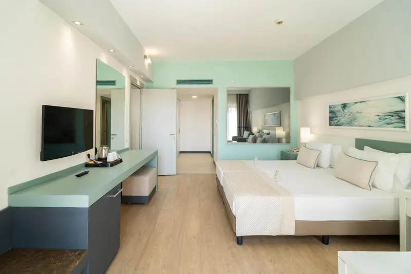 Chambre lumineuse avec un grand lit et un téléviseur à écran plat.