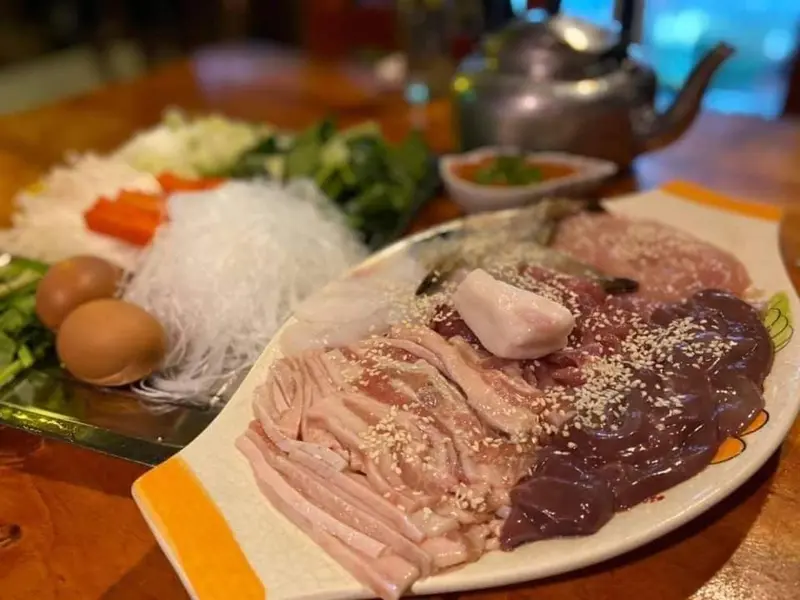 Assiette de crudités et de viandes froides disposées sur une table en bois.