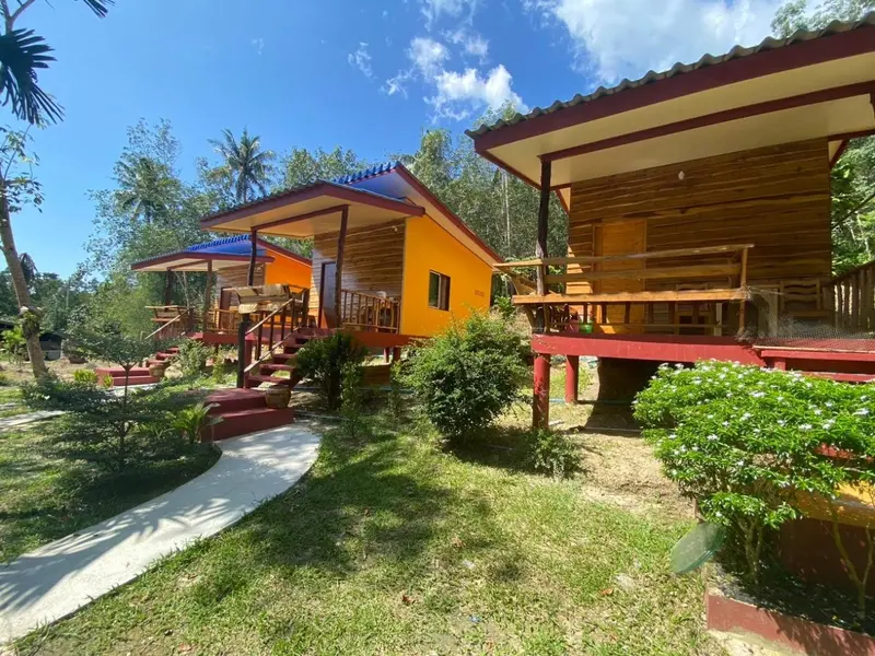 Petites maisons colorées sur pilotis au milieu d'une végétation luxuriante.