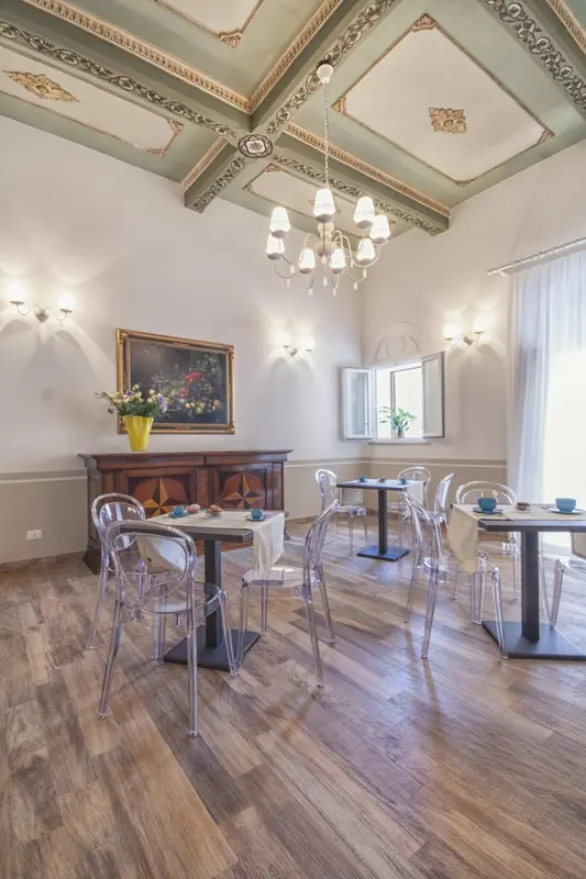 Une salle lumineuse avec des tables et des chaises transparentes, décorée de lustres et de tableaux.