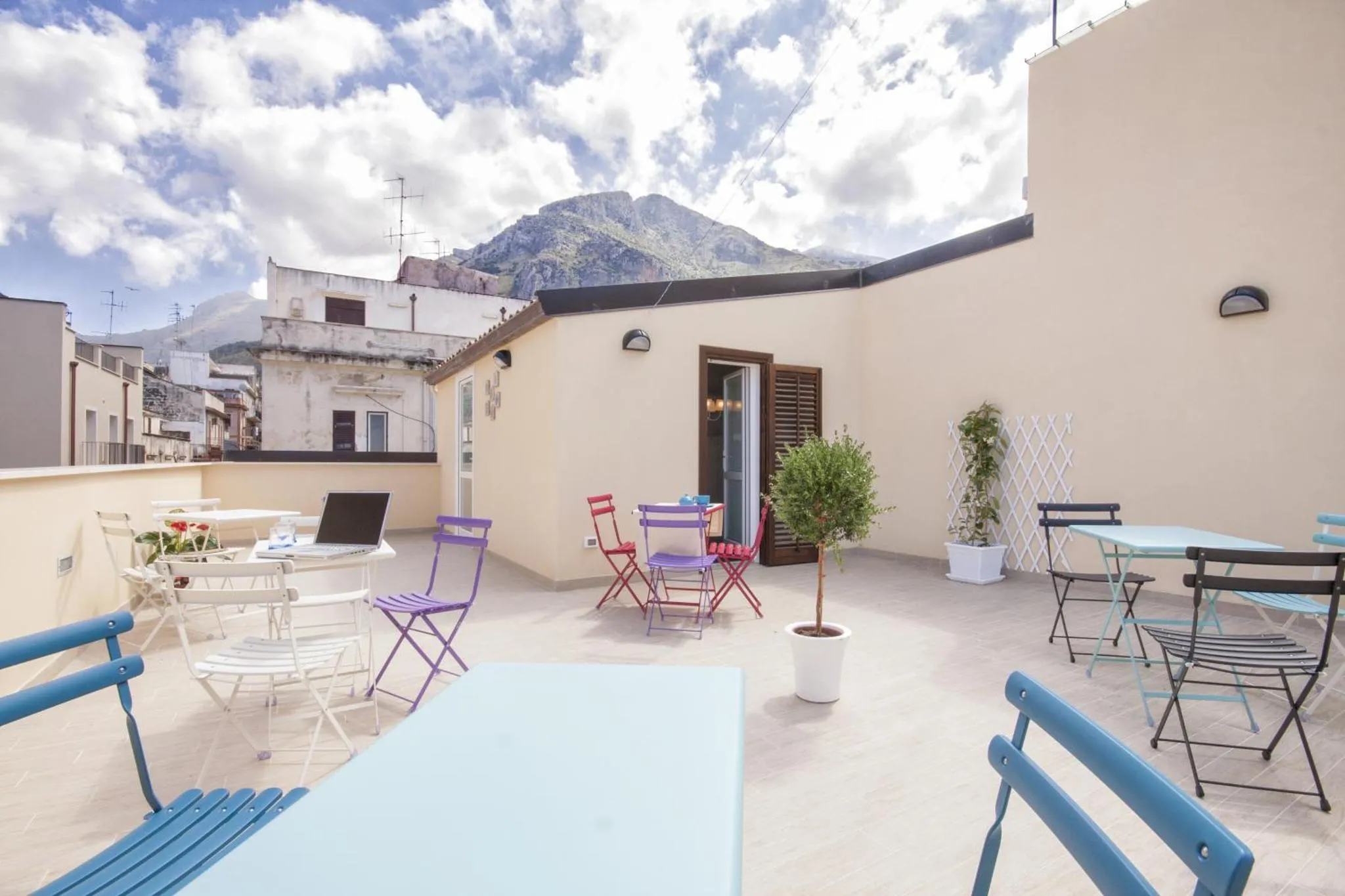 Terrasse aménagée avec tables et chaises offrant une vue sur les montagnes.