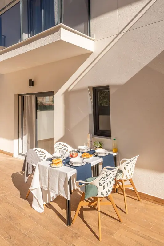 Une table est dressée pour un repas sur une terrasse ensoleillée.