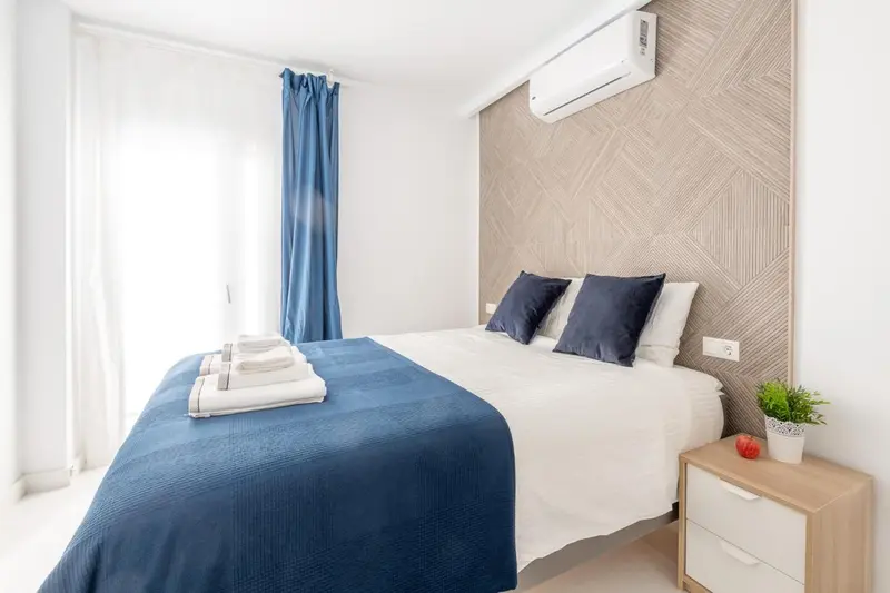 Une chambre lumineuse avec un lit fait et une décoration sobre.