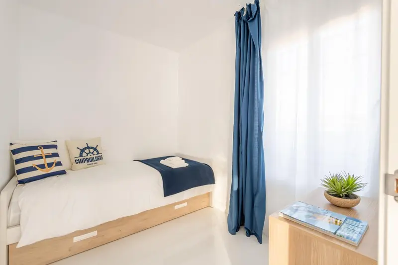 Une chambre lumineuse avec un lit simple et une décoration marine.